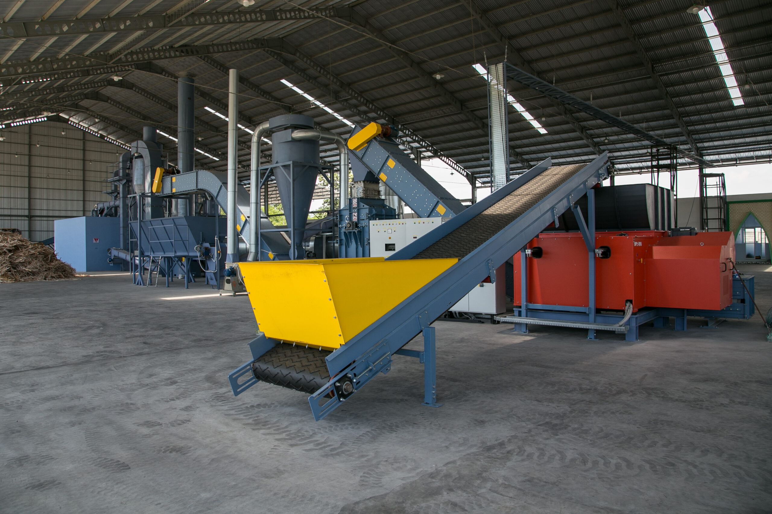 belt feeder for transporting wood waste to a chipper, chipper for grinding wood waste into chips